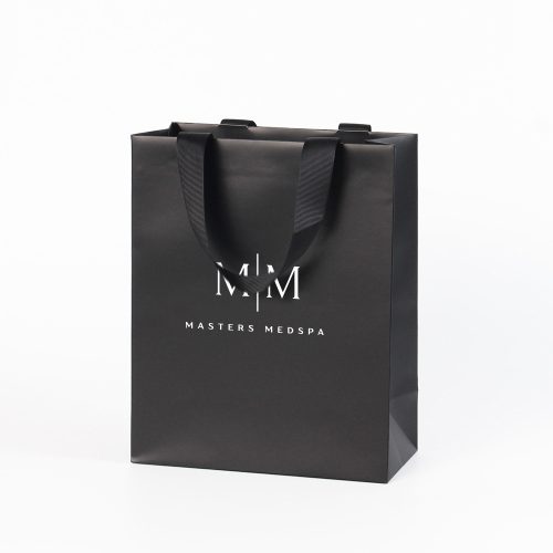 Medium matte black paper gift bag with black grosgrain ribbon handles and white logo, 8x10x5 inch, reinforced top and bottom boards